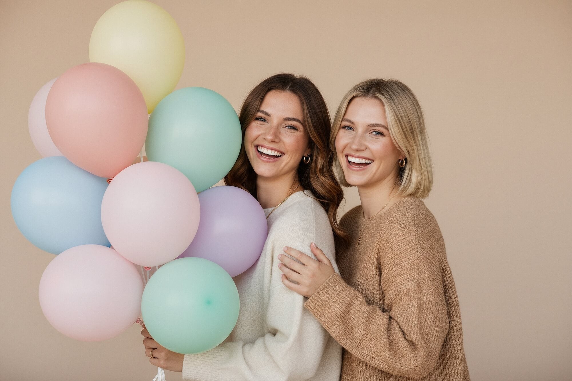 Two woman holding colorful balloons in a studio setting
